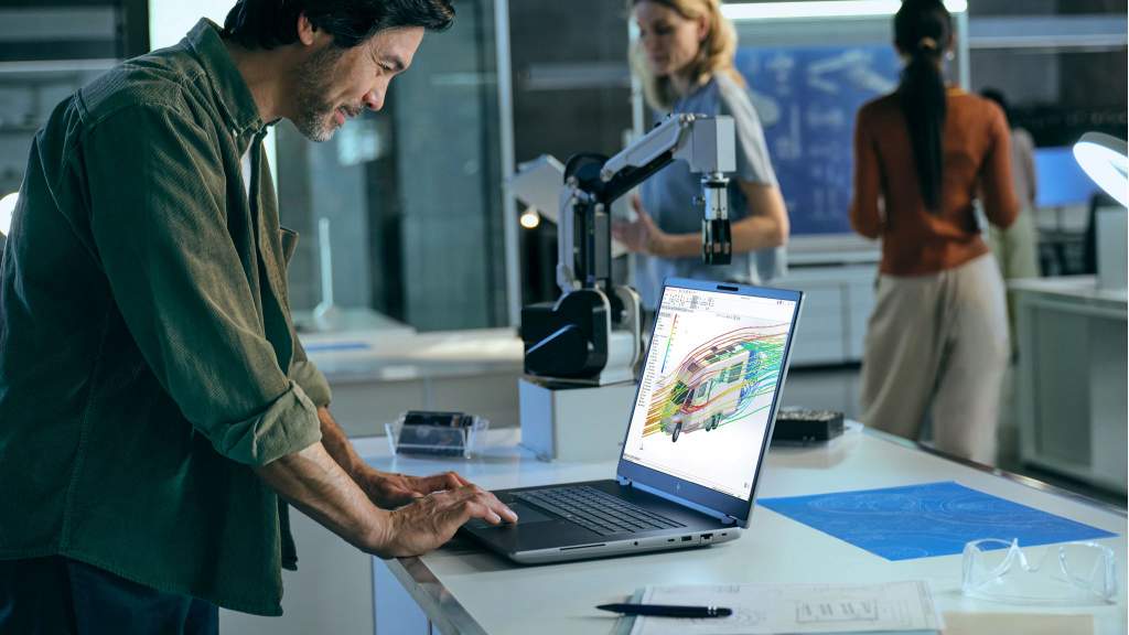 Inżynier pracujący na przenośnej stacji roboczej HP ZBook przy stanowisku z robotem